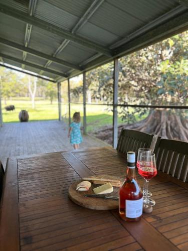 a wooden table with a bottle of wine and a glass at The Grandchester Cottage in Grandchester