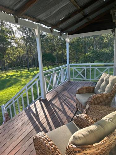 a porch with wicker chairs and chairs on a wooden deck at The Grandchester Cottage in Grandchester
