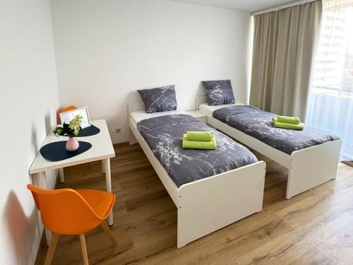 Una pequeña habitación con dos camas y un escritorio. en Bright Modern Apartment in Mülheim an der Ruhr, en Mülheim an der Ruhr