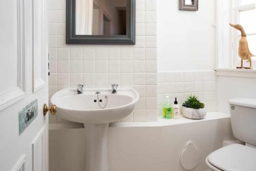 a white bathroom with a sink and a toilet at Teviot - Town Apt Wedding guest early check in in Hawick