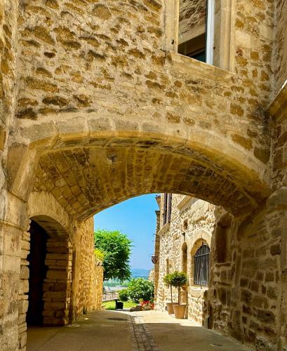 an old stone building with an archway in a street at Le Clos du Vialle in Grillon