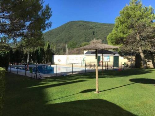 un ombrellone nell'erba accanto a una piscina di Esencia Pirineos l BQQ l Pisicina l Tenis a Biescas