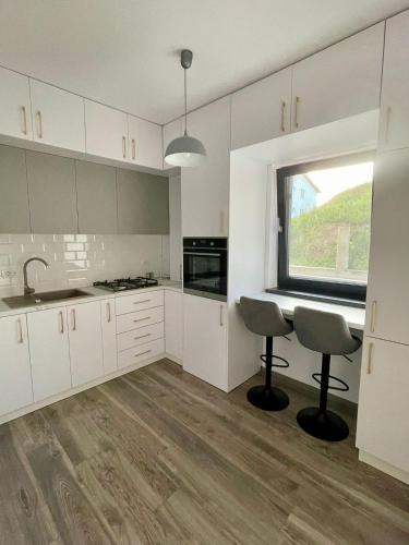 a kitchen with white cabinets and a window at Harmony Apartments Airport in Iaşi