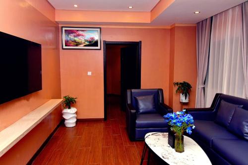 a waiting room with two blue chairs and a tv at Wealth Hotel Ikeja in Ikeja