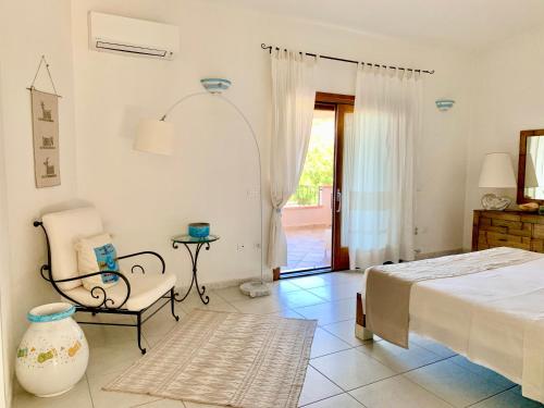 a bedroom with a bed and a chair and a window at Villa Starlight vista mare La Caletta in Santa Lucia