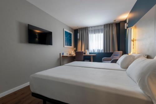 a hotel room with two beds and a desk at Travelodge Málaga Airport in Málaga
