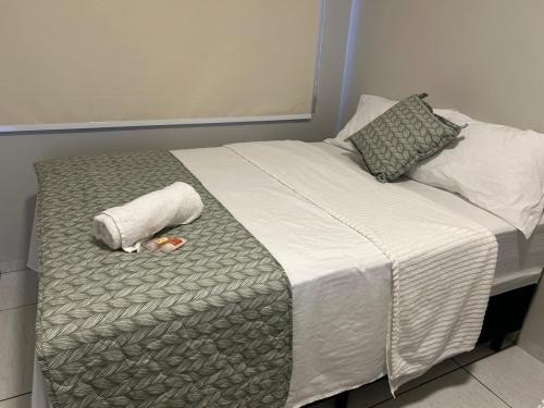 a bed with a towel and two pillows on it at Casa 02 - Casa com 2 quartos, próximo a rodoviária e aeroporto in Palmas