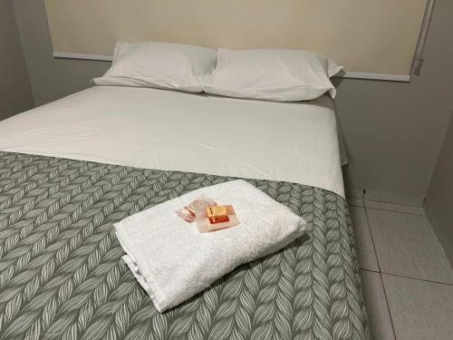a bed with a towel and a book on it at Casa 02 - Casa com 2 quartos, próximo a rodoviária e aeroporto in Palmas