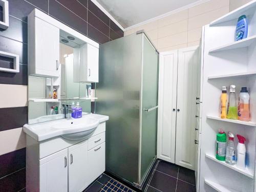 een badkamer met douche, wastafel en spiegel bij London apartments 2 in Pristina