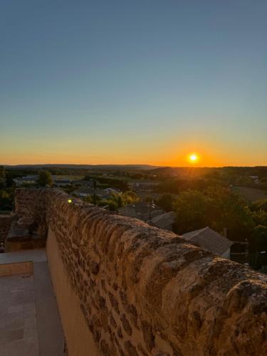 a sunset behind a stone wall with the sun in the background at Le Clos du Vialle in Grillon