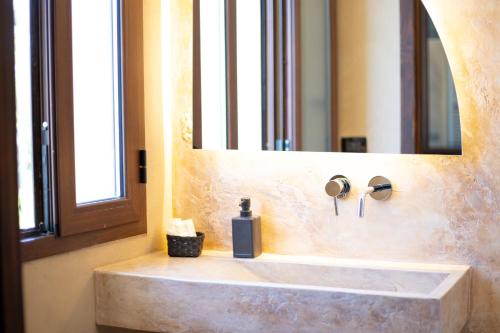 a bathroom sink with a soap dispenser sitting under a mirror at Bed & Breakfast Giardini Di Marzo in Lecce