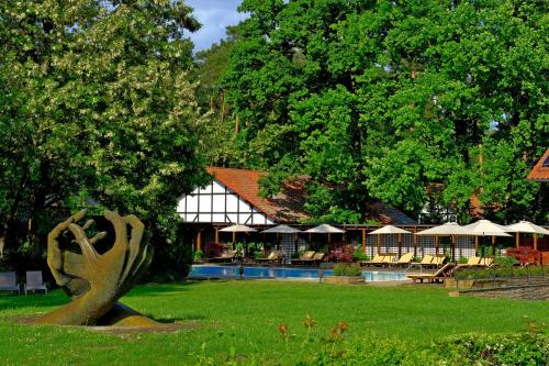 a statue in the grass in front of a building at Hotel Gut Klostermühle natur resort & medical spa in Alt Madlitz
