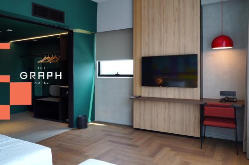 a room with a bed and a tv and a desk at The Graph Hotel in Kuala Lumpur