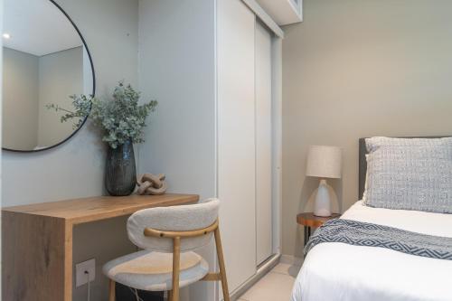 a bedroom with a mirror and a chair next to a bed at Zimbali Suites 617 in Ballito