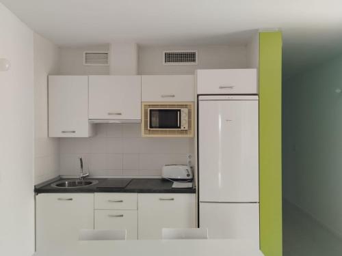 Una cocina con gabinetes blancos y un microondas. en Camping El Burgo, en Orellana la Vieja
