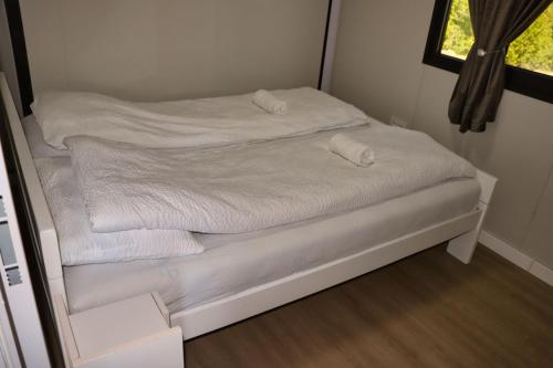 a small bed with white sheets and a window at Rama holiday resort in Prozor