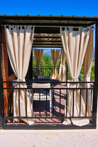 a balcony with curtains and a table on a porch at Rama holiday resort in Prozor