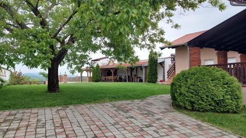 a house with a tree and a brick walkway at Kuća za odmor Tihi raj 
