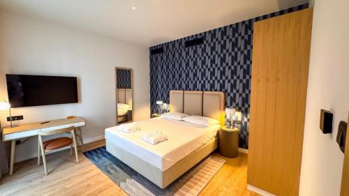 a bedroom with a bed and a desk and a television at Qumi Porto Suites in Tivat