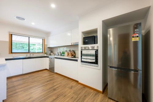 a kitchen with white cabinets and a stainless steel refrigerator at Elegant Country Escape in Horsham
