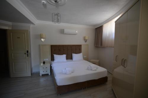 a bedroom with a white bed with towels on it at Funda Hotel in Göcek