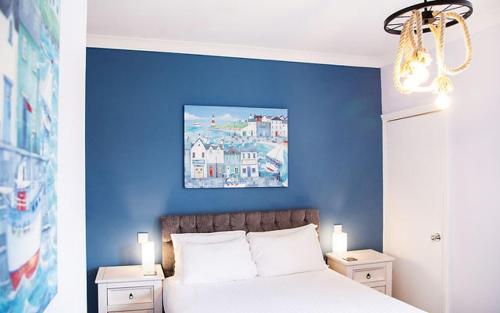a blue bedroom with a bed with two night stands at The Montana in Torquay