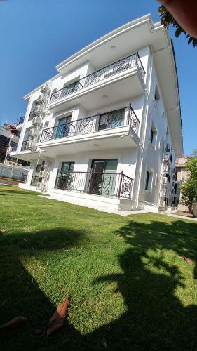 a large white building with a lawn in front of it at Arti̇m Apart Hotel in Fethiye