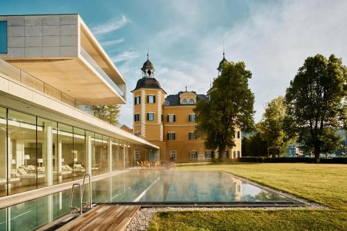 a house with a swimming pool in front of a building at Falkensteiner Schlosshotel Velden – The Leading Hotels of the World in Velden am Wörthersee