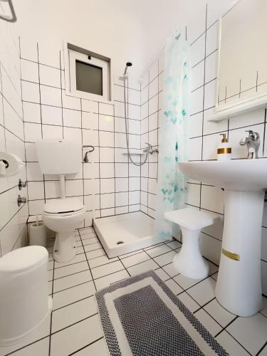 a white bathroom with a sink and a toilet at Maria's Rooms in Skala Rachoniou