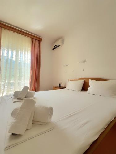a large white bed with white pillows and a window at Maria's Rooms in Skala Rachoniou