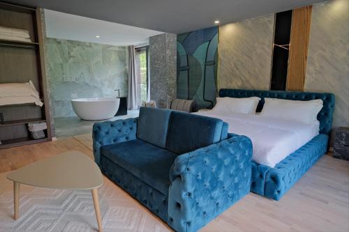 a bedroom with a blue couch and a bed and a tub at Hotel Valbor in Tropojë