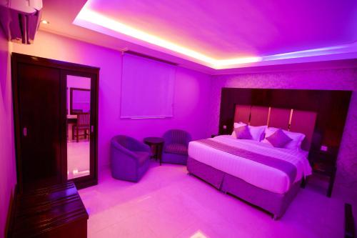 a purple bedroom with a bed and a chair at Nova Park Serviced Apartments - نووا بارك للشقق المخدومة in Yanbu