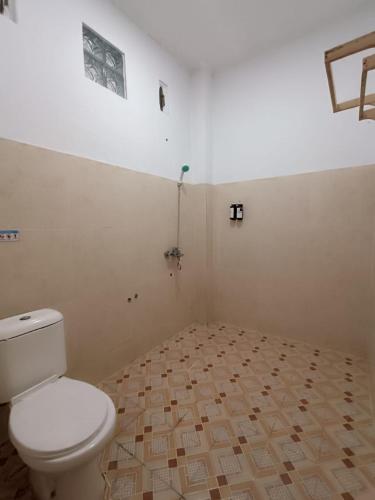 a bathroom with a toilet and a tile floor at D'Hills Hotel in Bukittinggi