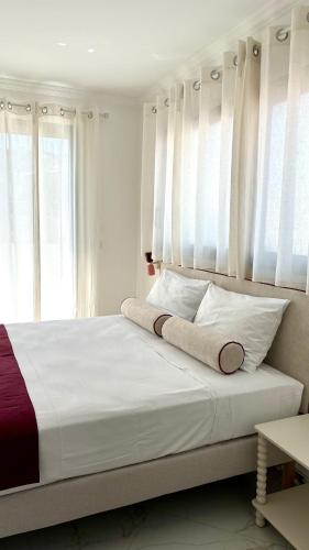a bedroom with a bed with white sheets and windows at Hotel et Appartements Reine D'Azur in Roquebrune-Cap-Martin