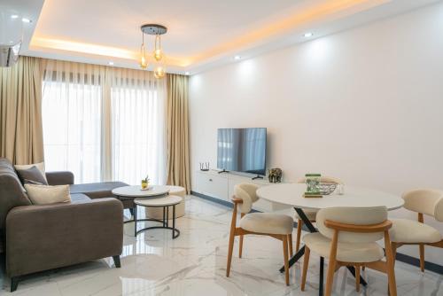 a living room with a couch and tables and a tv at Palmera Resort Wellness & SPA in Kérynia
