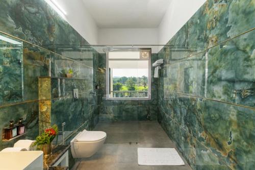 a bathroom with a toilet and a window at JHADOL BAGH - A Riverside Retreat in Jharol