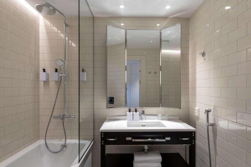 a bathroom with a tub and a sink and a shower at Scandic Grand Central Helsinki in Helsinki