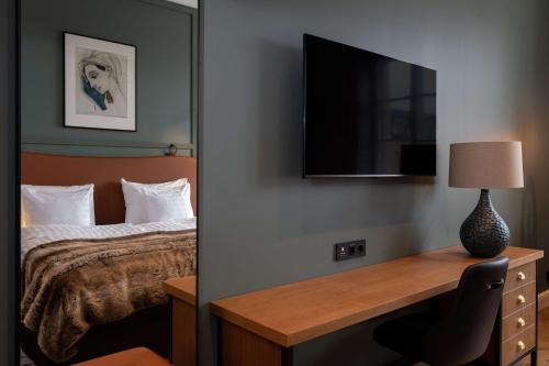 a hotel room with a bed and a desk with a television at Scandic Grand Central Helsinki in Helsinki
