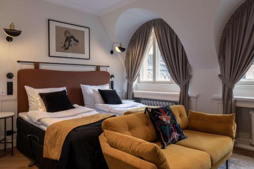 a bedroom with a bed and a couch and a window at Scandic Grand Central Helsinki in Helsinki