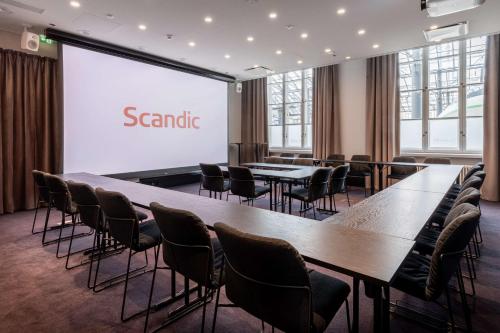 a conference room with tables and chairs in front of a screen at Scandic Grand Central Helsinki in Helsinki