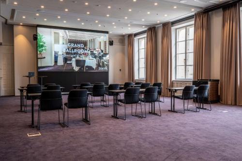 a room with chairs and tables and a screen at Scandic Grand Central Helsinki in Helsinki