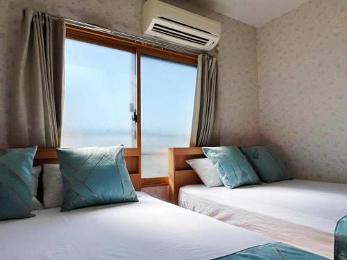 a room with two beds and a window with a view at Osaka Enso無料駐車場ありUSJまで15分難波へ15分電車直通 in Osaka
