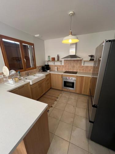 a kitchen with wooden cabinets and a black refrigerator at Cocon familial moderne et au calme à 1h30 de Paris 