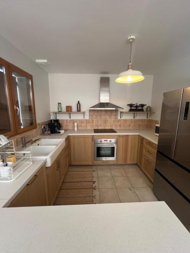 a kitchen with wooden cabinets and stainless steel appliances at Cocon familial moderne et au calme à 1h30 de Paris 