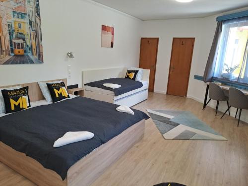 a bedroom with two beds and a desk and a window at Május 1 Vendégház - Szombathely in Szombathely