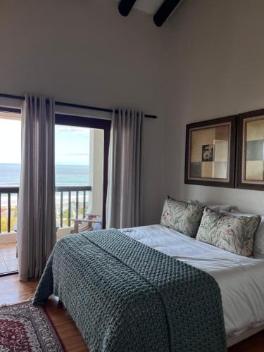 a bedroom with a bed with a view of the ocean at Vistas al Mar in Groot Brak Rivier