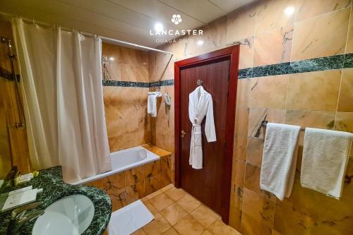 a bathroom with a shower and a tub and a sink at Lancaster Ouaga 2000 in Ouagadougou