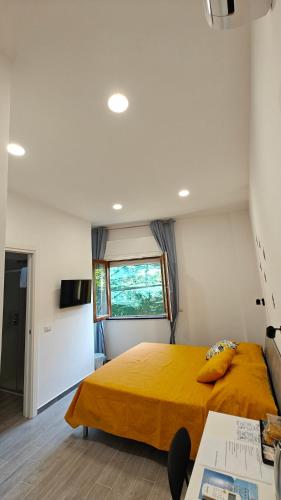 a bedroom with a yellow bed and a window at Swallow Room Holidays in Massa Lubrense