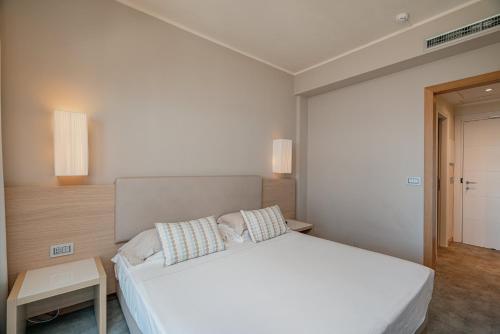 a bedroom with a large white bed with two pillows at Hotel Calabona in Alghero