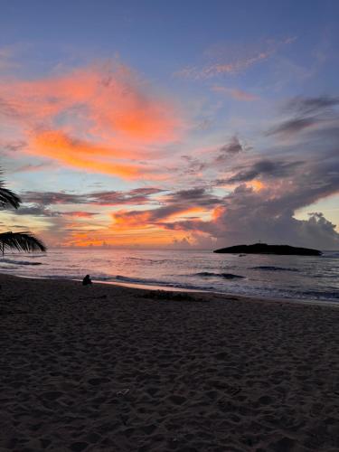 a person sitting on the beach at sunset at Brusea by the Beach in Camuy
